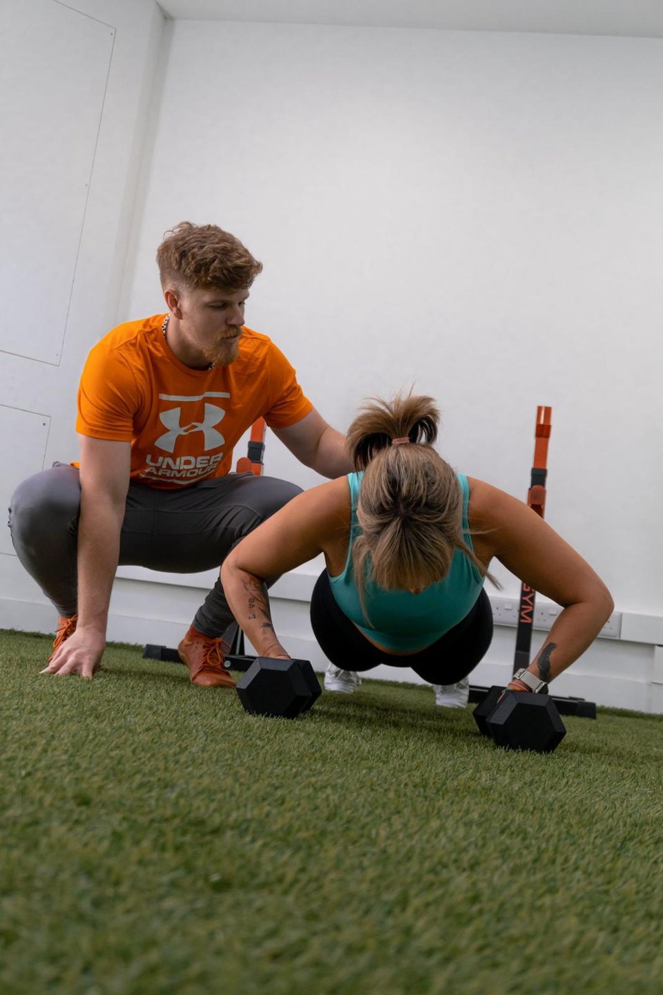 Victor giving hands-on cues to a client holding a kettlebell plank
