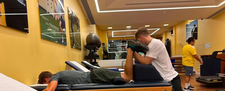 Hands-on sports therapy for a client lying face down on a treatment plinth
